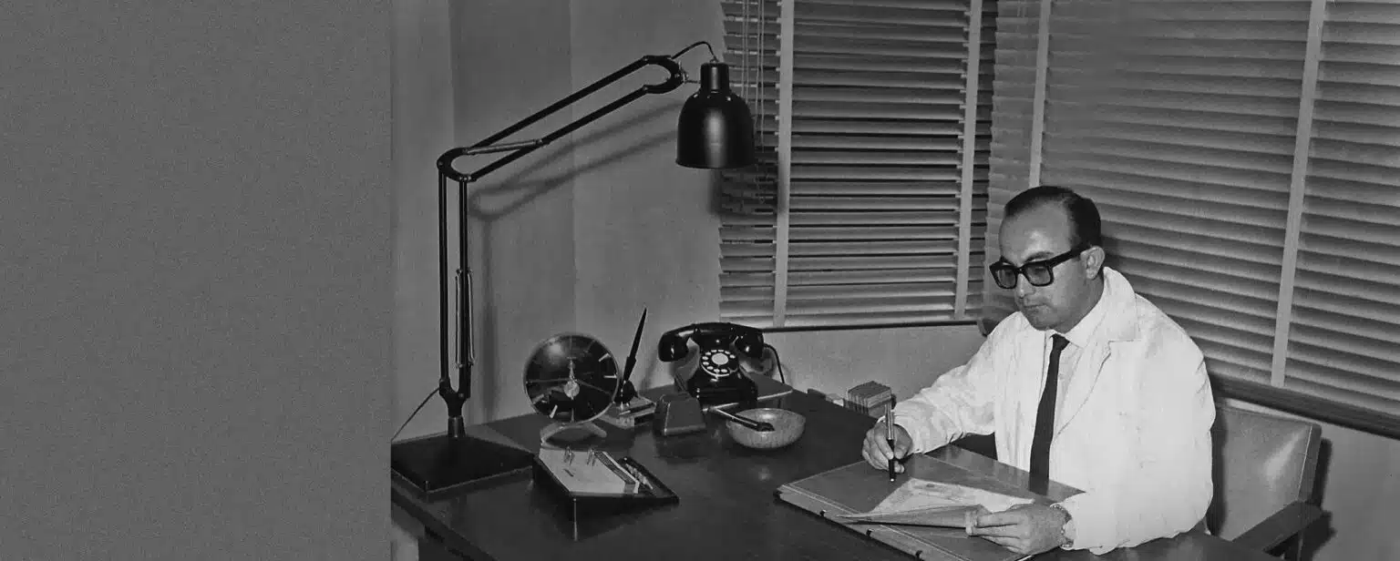 Photo en noir et blanc d’Alfonso Caycedo jeune, assis à son bureau